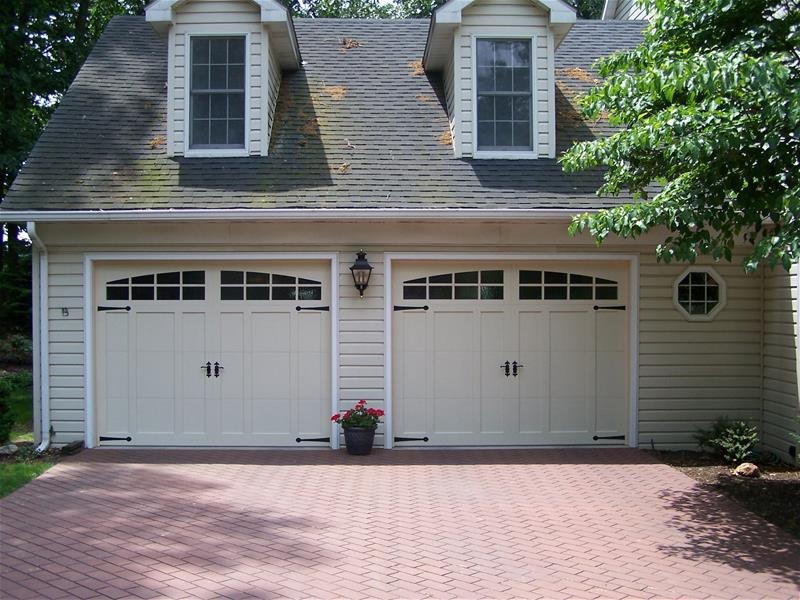 Two carriage-style garage doors on a home with a brick paver driveway