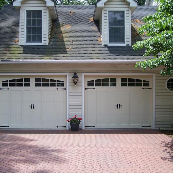 Two carriage-style garage doors on a home with a brick paver driveway