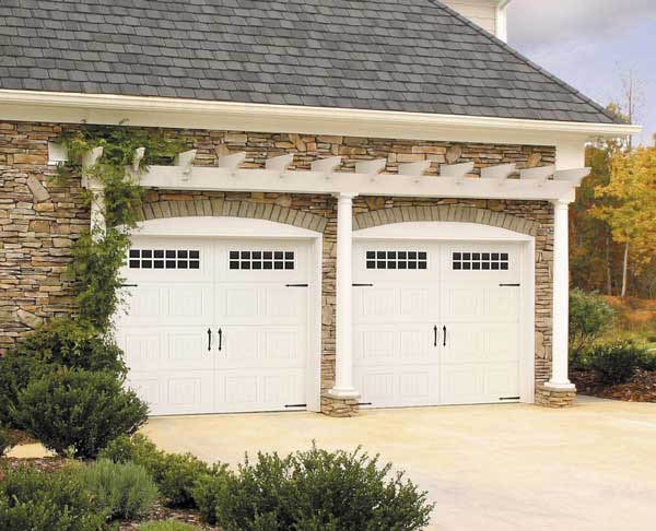 A home with two white carriage-style garage doors under a stone arch